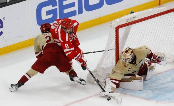 A Boston College player lays a check on a BU player at the side of the net